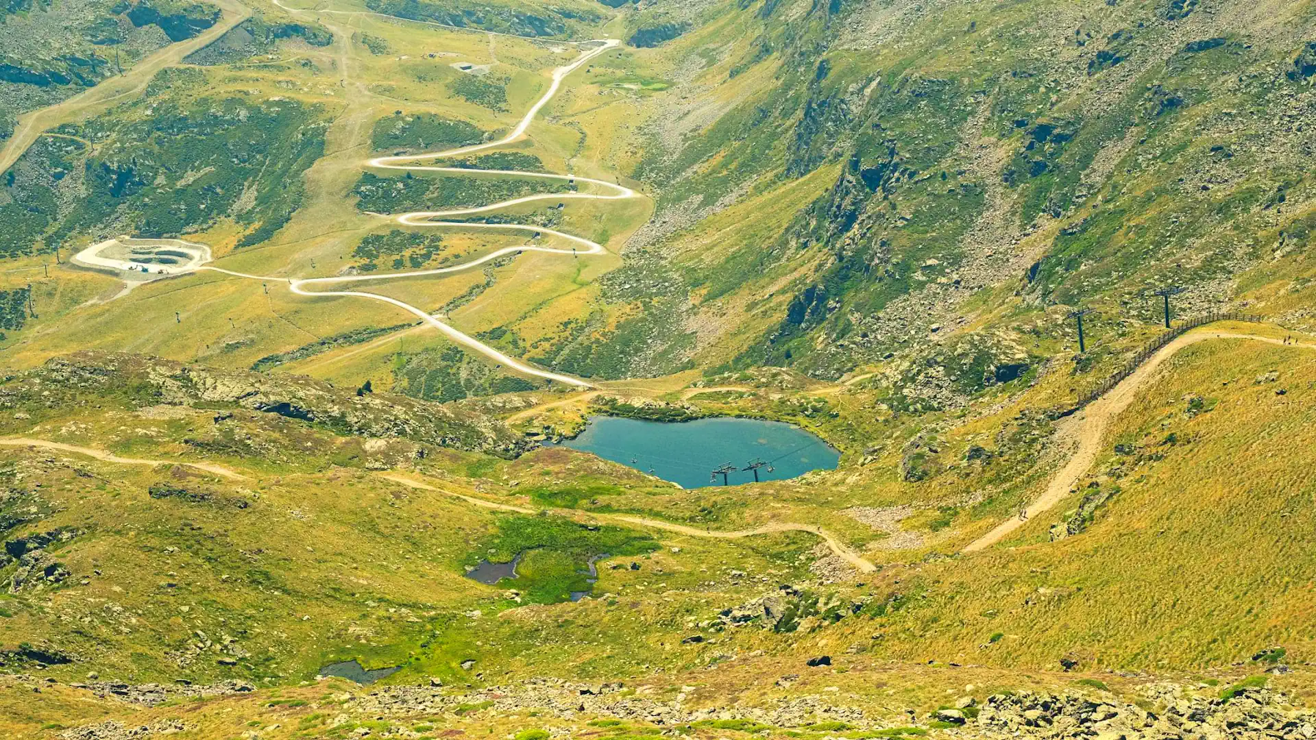 Hiking trails and winding mountain road in Andorra with alpine lake in the Pyrenees